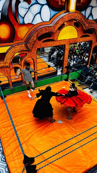 A boxing ring with two people in traditional attire, a referee, and spectators. 5