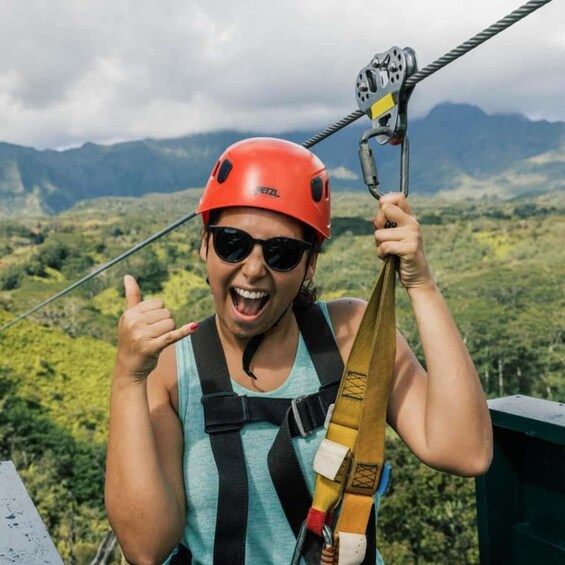 A person wearing a red helmet and a harness, holding onto a zip line. 4