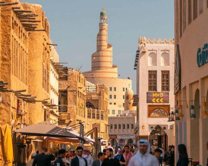 A bustling street with a prominent spiral minaret, traditional architecture, and a crowd of people. 5