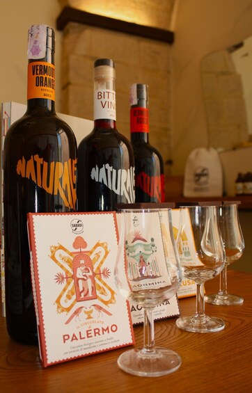 Three bottles of wine, two glasses, and a box of 'Palermo' chocolates. 2