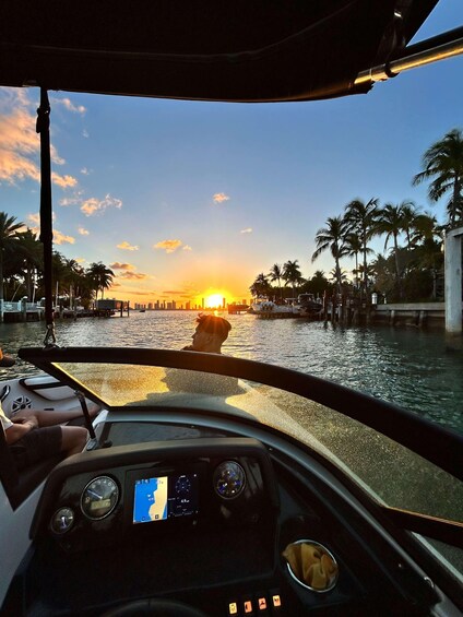 A sunset over water with palm trees and a city skyline in the background. 2