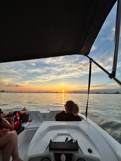 A boat with two people on deck, a sunset in the background, and a calm water body. 3