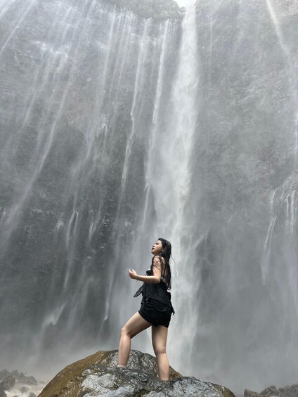 A person standing on a rock with a waterfall in the background. 4