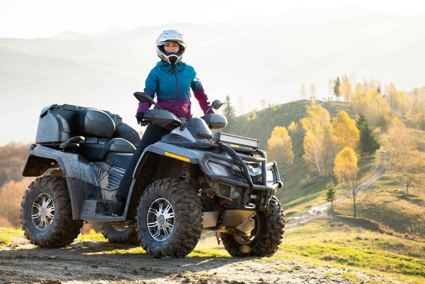 Eine Person fährt mit einem Quad durch eine hügelige Herbstlandschaft. 2