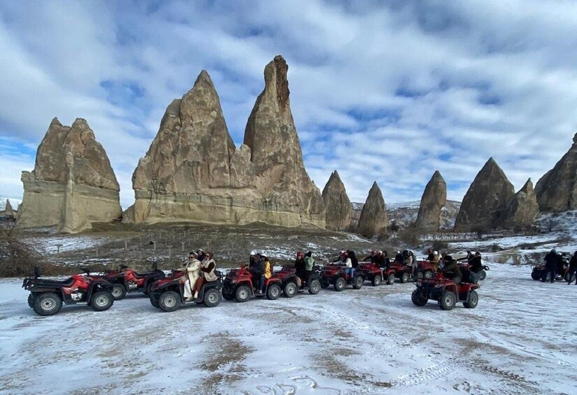 A group of people on ATVs in a snowy landscape with distinctive rock formations. 5