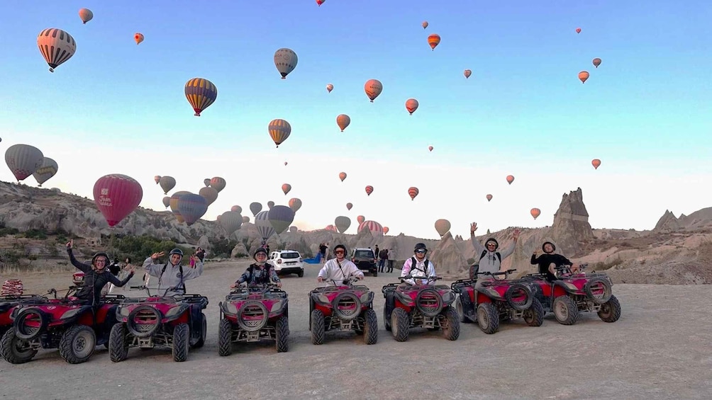 A group of people on ATVs with hot air balloons in the background. 1