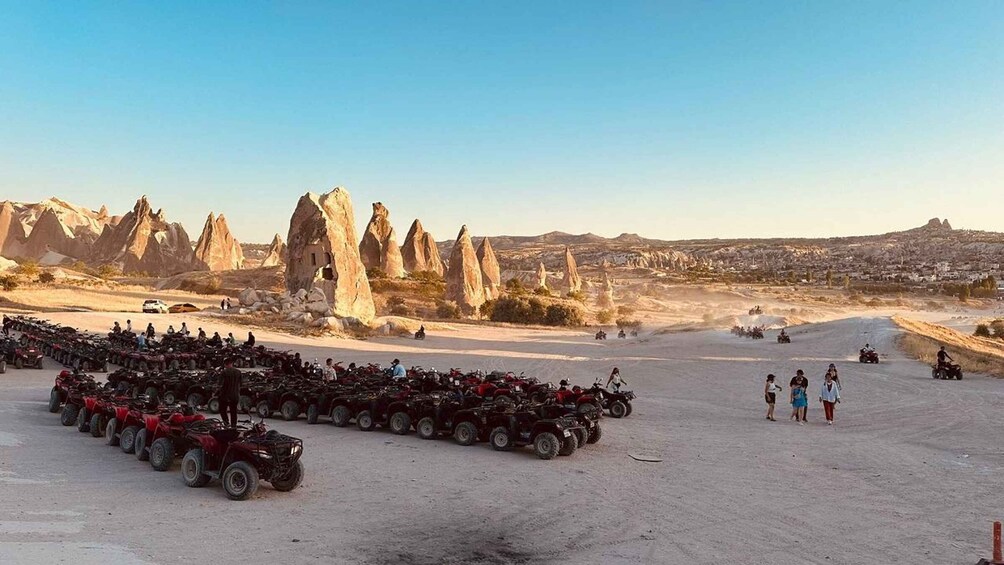 A desert landscape with rock formations and a group of ATVs parked in the foreground. 3