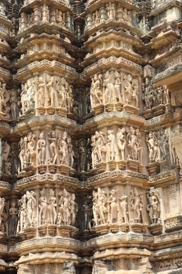 A detailed stone carving of multiple figures on a temple facade. 4