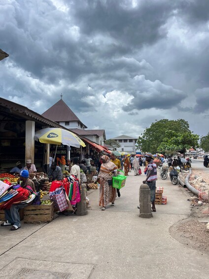 Un mercado al aire libre concurrido, donde vendedores ofrecen frutas y verduras bajo sombrillas. 4
