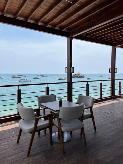 Una terraza de madera con una mesa y sillas que dan al mar. 1