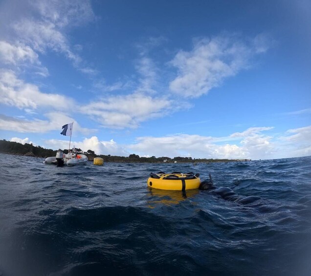 A body of water with a yellow inflatable raft and a sailboat with a flag. 3