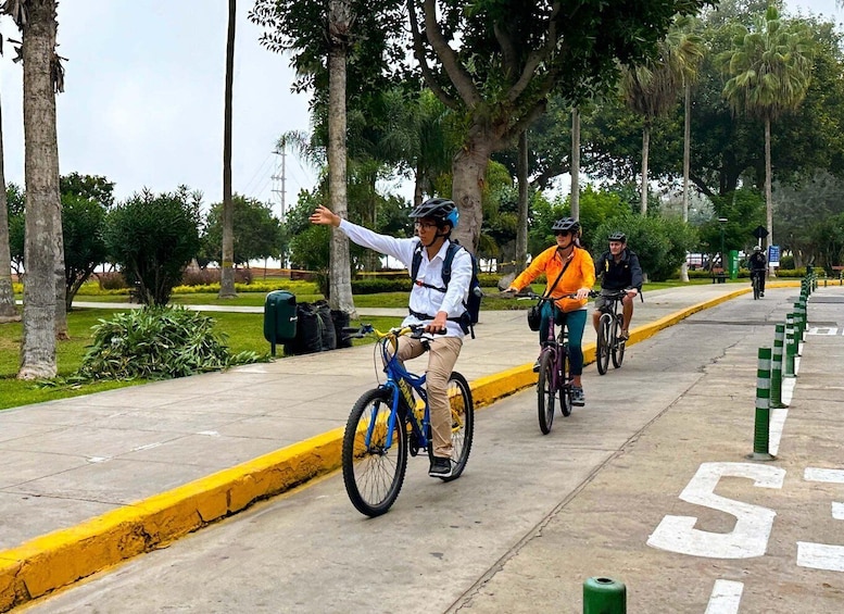 A group of cyclists on a paved path with trees and greenery on the sides. 1