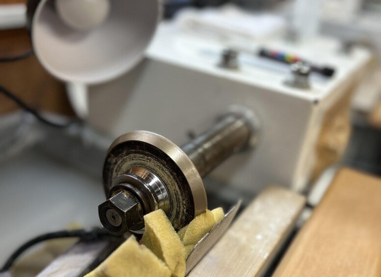 A lathe machine with a metal piece being machined, a tool rest, and a control panel. 5