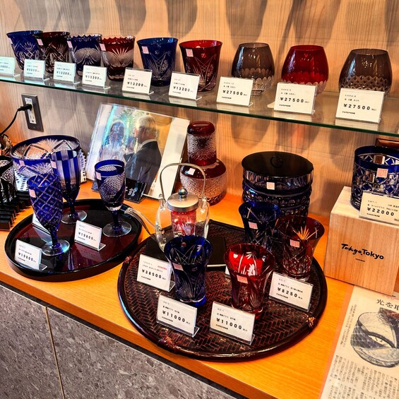 A variety of glassware displayed on shelves and trays with price tags. 2