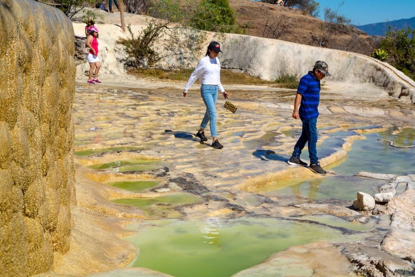 People walking on mineral-rich terraces with green pools. 4