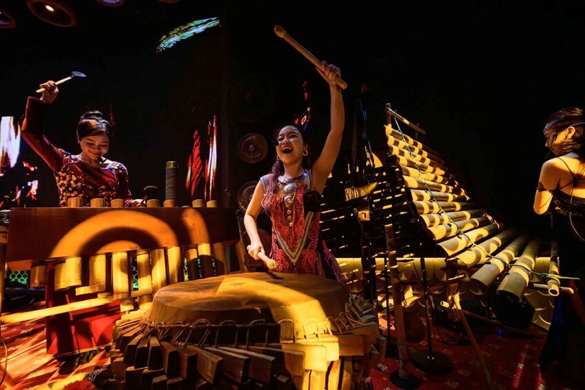 A person playing a large drum, surrounded by other musical instruments and performers. 5