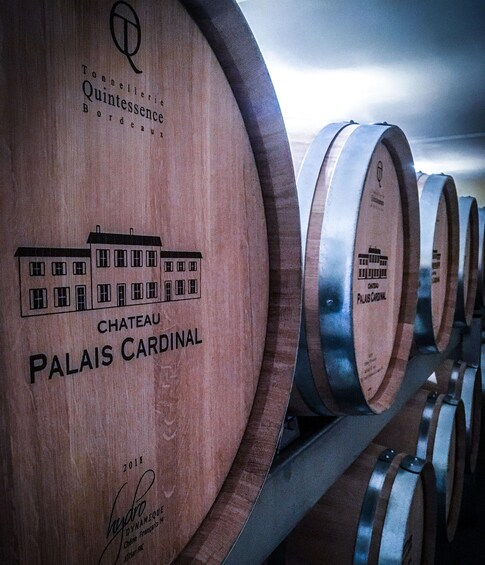Wooden wine barrels with Chateau Palais Cardinal branding, arranged in a row. 3