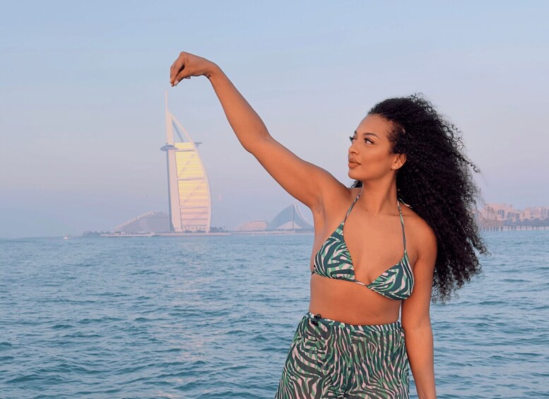 A person in a bikini standing by the sea with a distinctive sail-shaped building in the background. 5