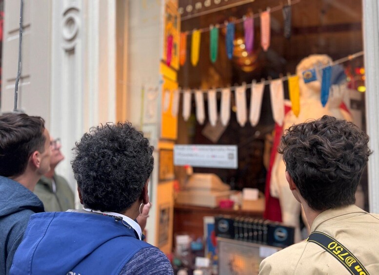 Tre personer foran en butik med farverige flag. 5