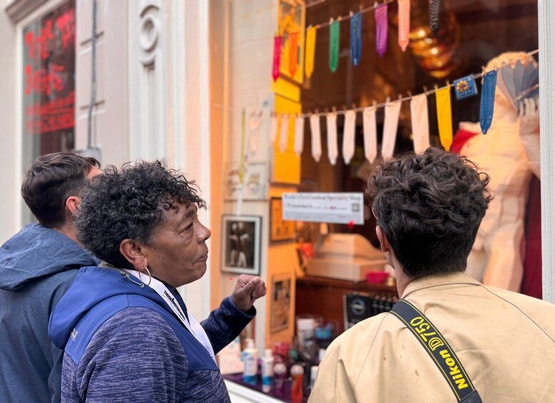 Et gadesceneri med mennesker foran et butiksvindue, der viser farverige flag og en mannequin. 1