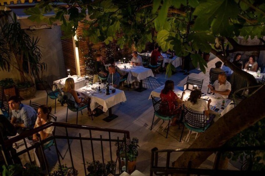 An outdoor restaurant with tables and chairs, surrounded by greenery. 3