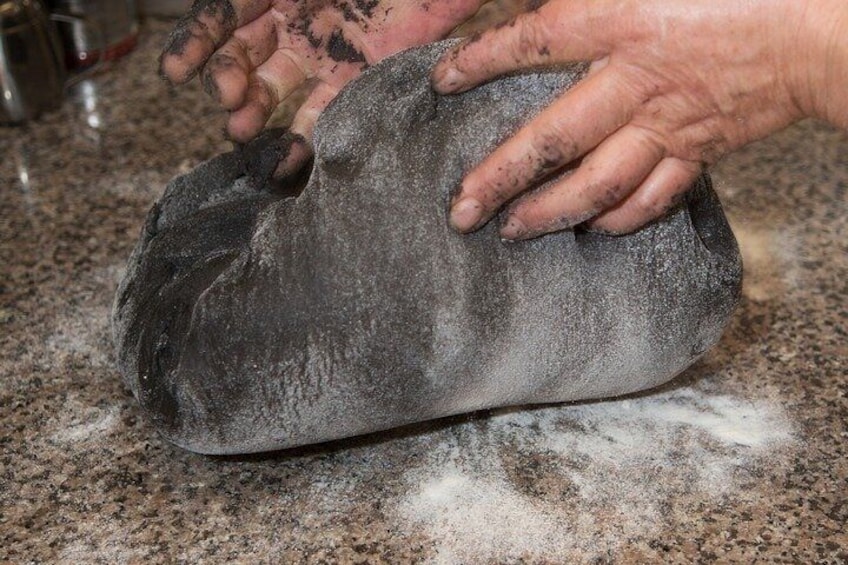 A person handling a large, dark, dusty object on a granite countertop. 4