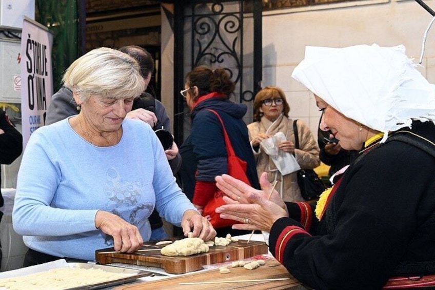Two people at a food stall, one cutting dough. 1