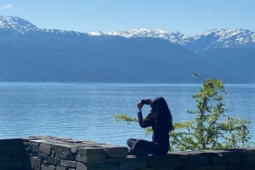 A person taking a photo of a lake with mountains in the background. 3