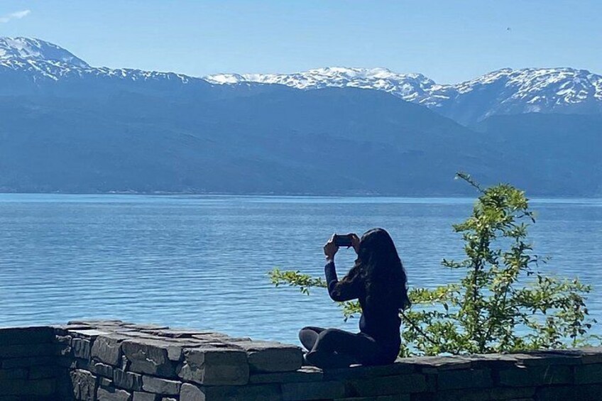 A person taking a photo of a lake with mountains in the background. 2