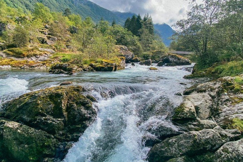 A river flowing through a mountainous landscape with rocky terrain and lush greenery. 3