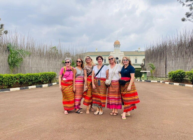 A group of people standing in front of a building with a dome and a fence with tall grass. 1