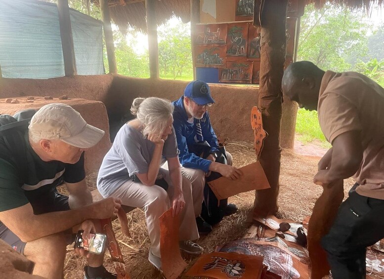 A group of people sitting on a thatched roof structure, engaged in an activity with a map and some documents. 5