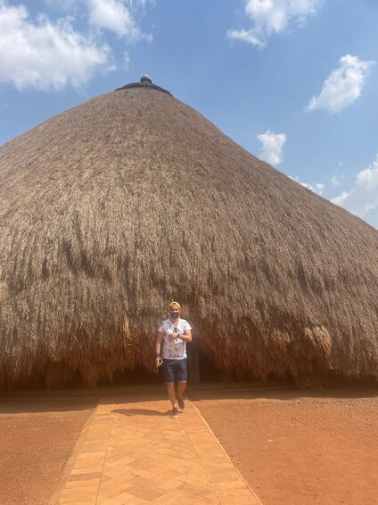 A person standing in front of a large thatched structure. 3