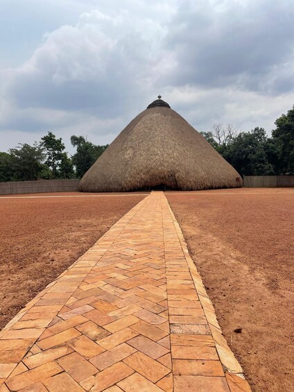 A large thatched structure with a paved pathway leading to it. 5