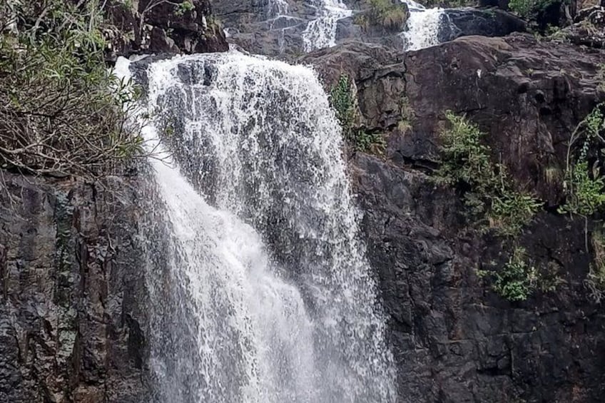 A waterfall cascading over rocky terrain with sparse vegetation. 1