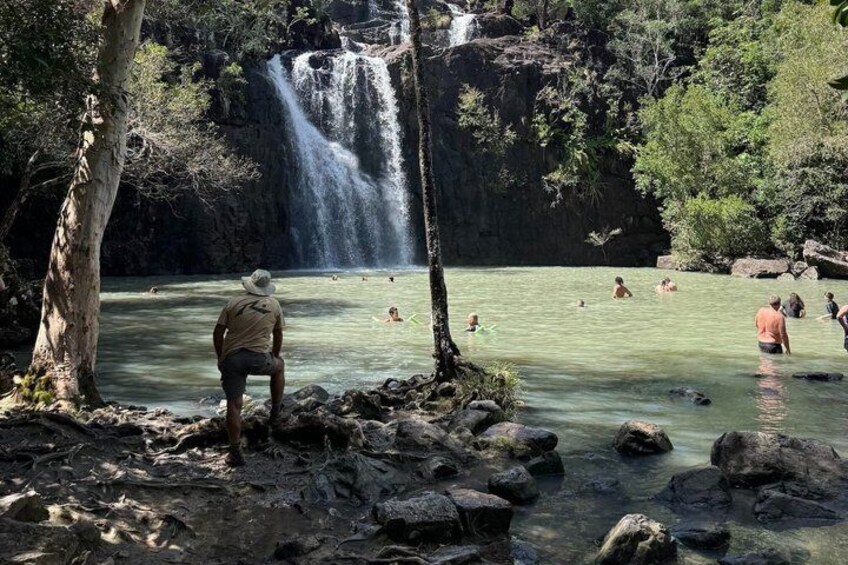 A waterfall, clear water, and people swimming. 3