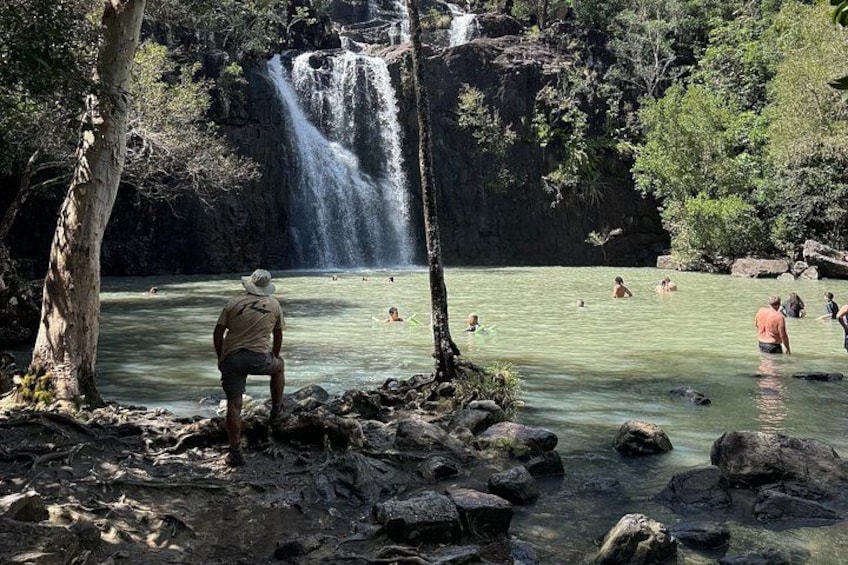 A waterfall, clear water, and people swimming. 2