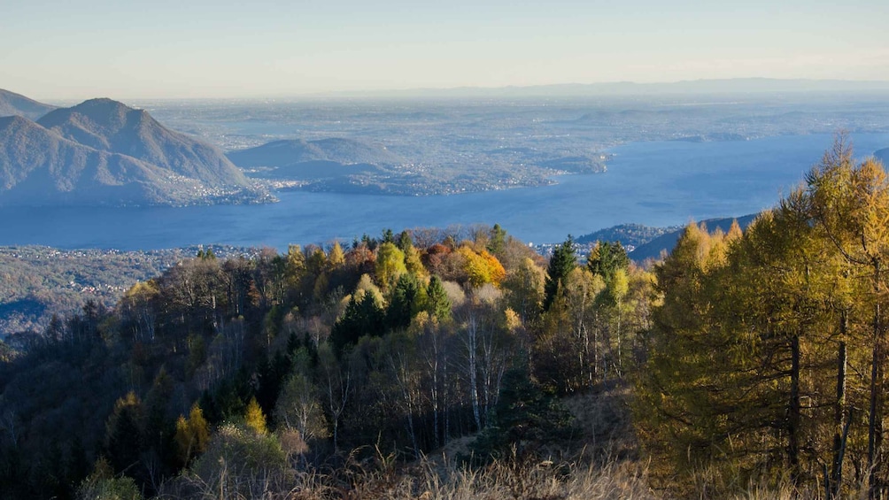 A mountainous landscape with autumn foliage, a valley, and a distant body of water. 1