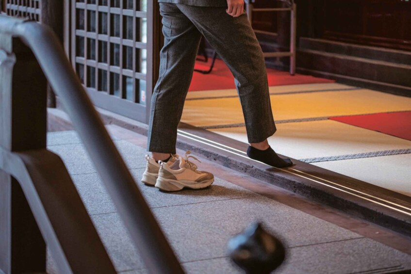 A person walking on a patterned carpet with a railing and steps in the background. 4