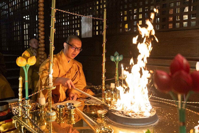 A monk performing a ritual with a fire altar, surrounded by ritual items and incense. 2