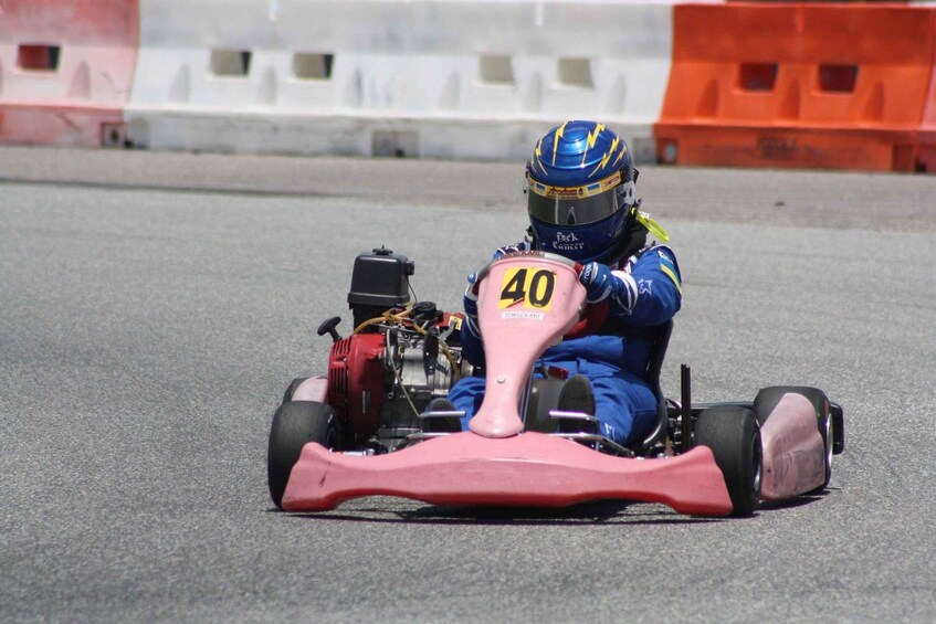 A go-kart racer in blue gear with the number 40 on the front, on a race track. 1