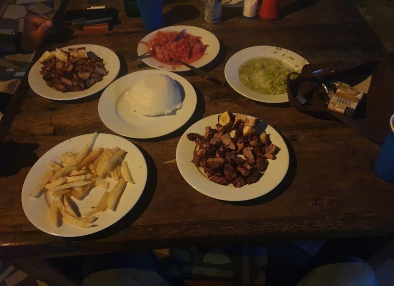 A wooden table with plates of food including fries, meat, and a white dish that could be rice or mashed potatoes. 2