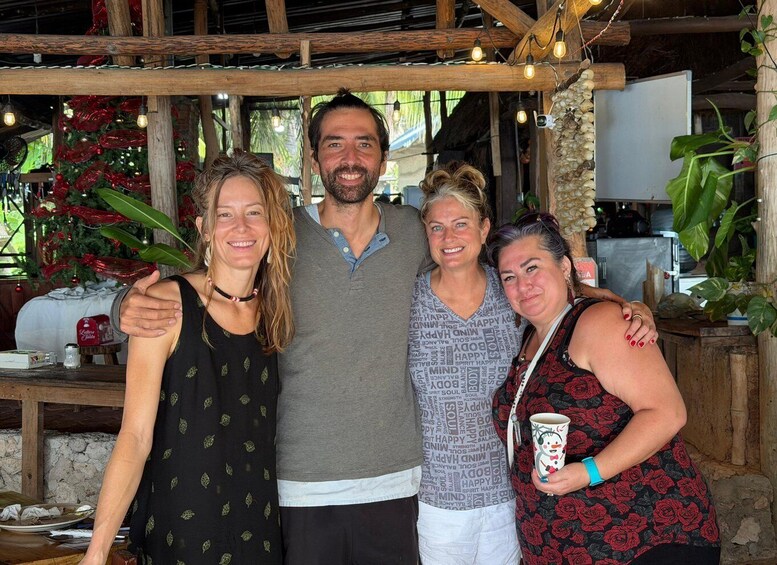 A group of people standing in a rustic outdoor setting with wooden beams and string lights. 3