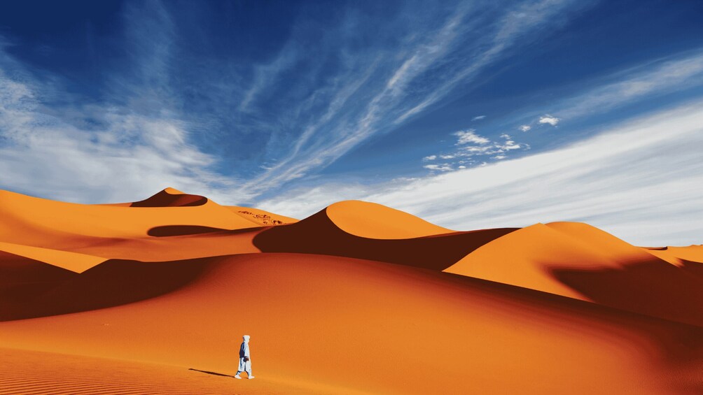 A desert landscape with sand dunes and a person walking. 2