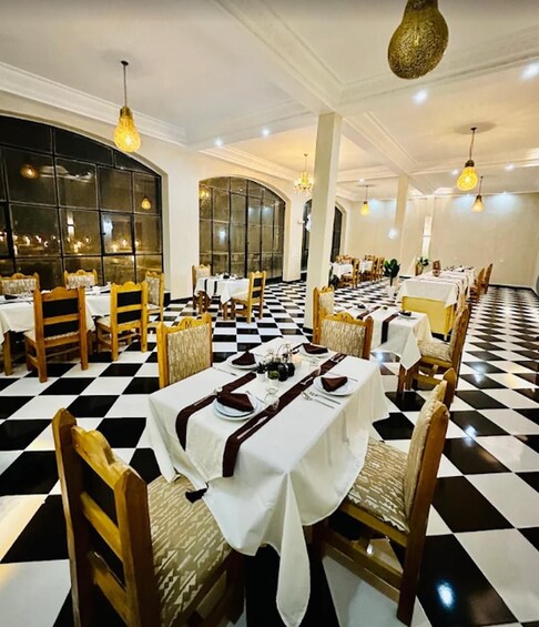 A restaurant with checkered flooring, wooden chairs, and tables set for dining. 5