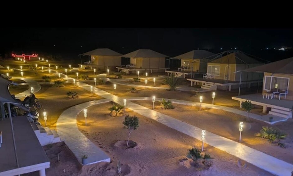 A well-lit resort area with multiple tents and pathways. 4