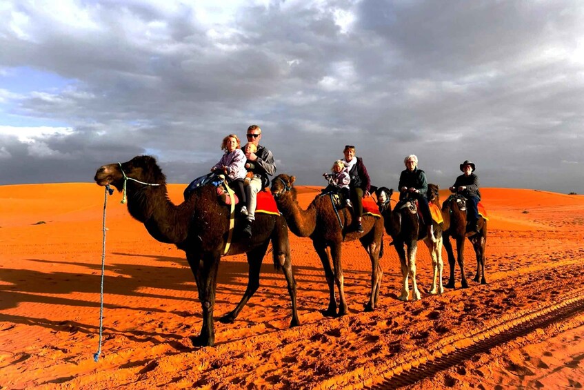 A group of people riding camels across a desert landscape. 3