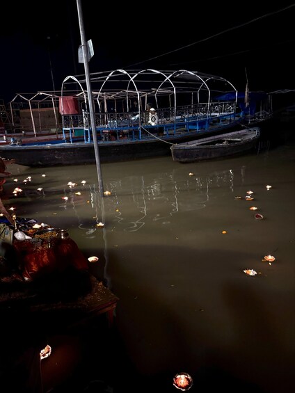 A nighttime river scene with floating candles and a dock with a covered structure. 5