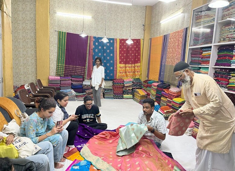 A fabric store with colorful textiles and a group of people examining fabrics. 4