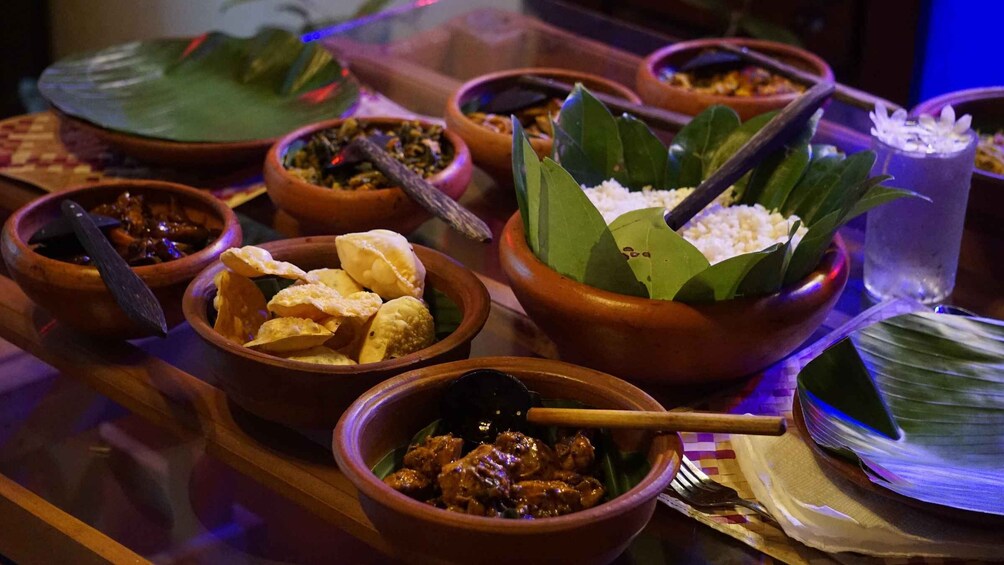 A variety of dishes served in traditional clay pots, including rice, meat, and snacks, with a blue-lit background. 3